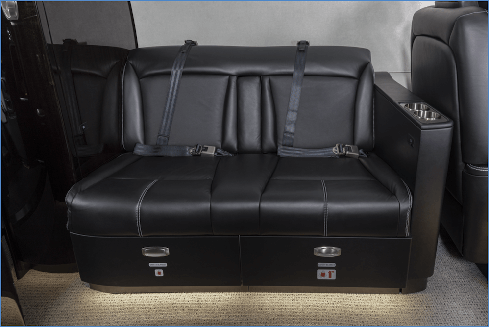 Tandem-style aircraft seating upholstered in black leather with under-seat storage, cupholders and seatbelts.
