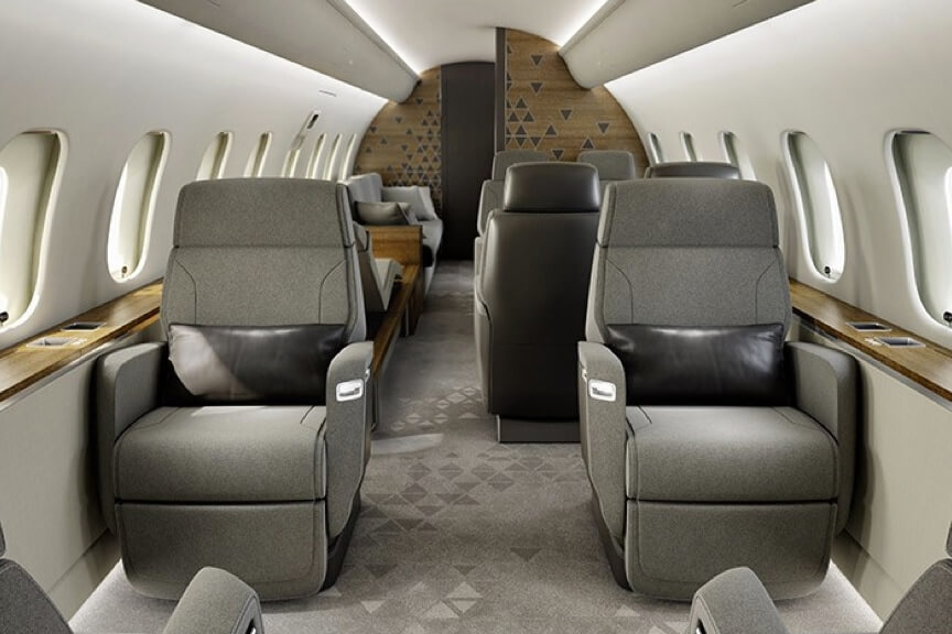 Bombardier-Global-5500-club-suite-featuring-gray-carpeting,-white-walls-and-Nuage-seats-with-gray-upholstery-and-black-leather-lumbar-pillows.
