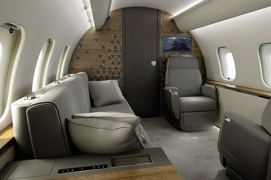 Global-5500-private-suite-with-gray-carpeting-and a-wood-paneled-wall. A-berthable-divan-sits-to-the-left-of-the-frame-and-Nuage-seats-in-a-club-configuration-and-a-bulkhead-monitor-are-on-the-right.