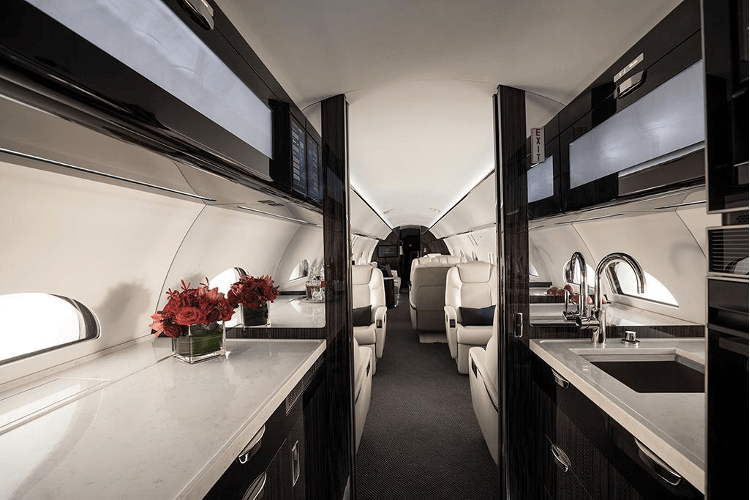 View from the G500 galley into the forward cabin. The galley features white stone countertops and dark paneling.