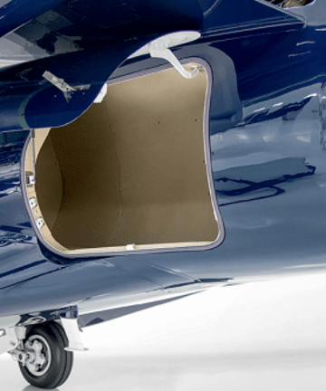 A compartment with a curved door sits open on the side of a dark blue airplane. 