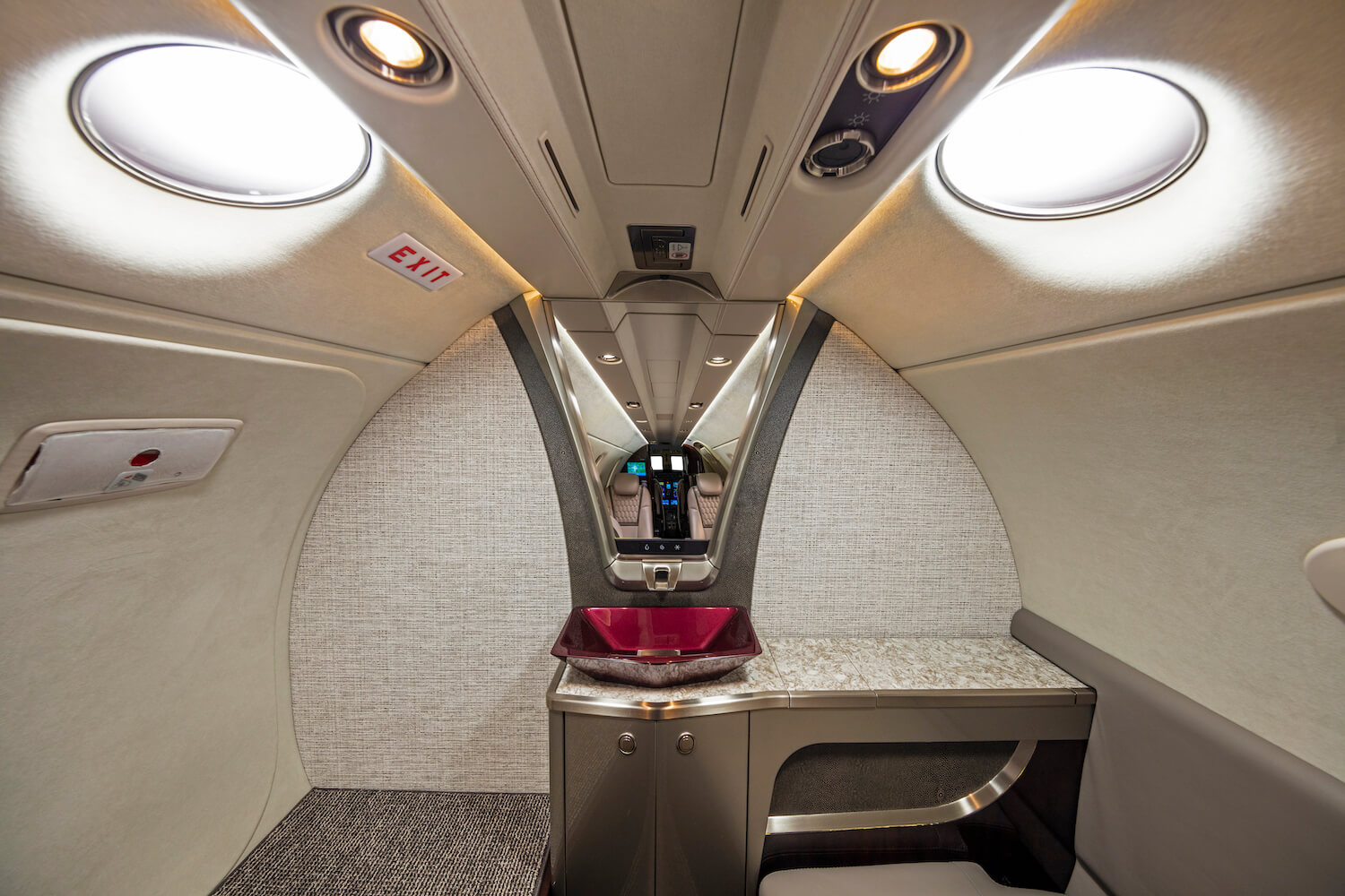 The-Cessna-Citation-CJ4-Gen2-bathroom,-with-light-gray-upholstery,-red-sink,-mirror-above-the-vanity-and-set-of-skylights. 