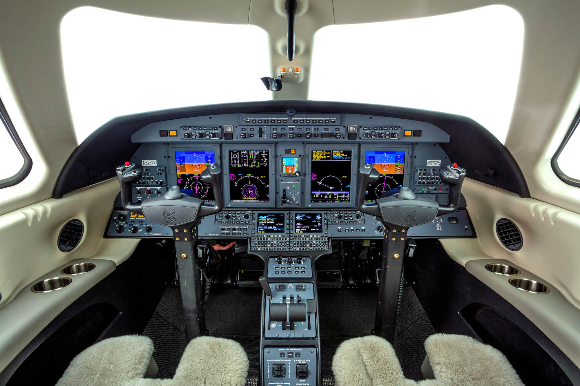 The-Cessna-Citation-CJ4-Gen2-cockpit,-with-shearling-lined-seats,-yokes-and-a-panel-of-display-screens-and-electronic-controls. 