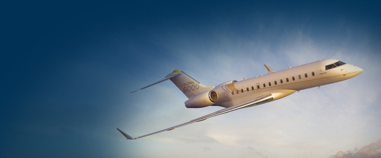 A long-range private jet in flight against a clear sky with soft clouds, during what appears to be sunrise or sunset.